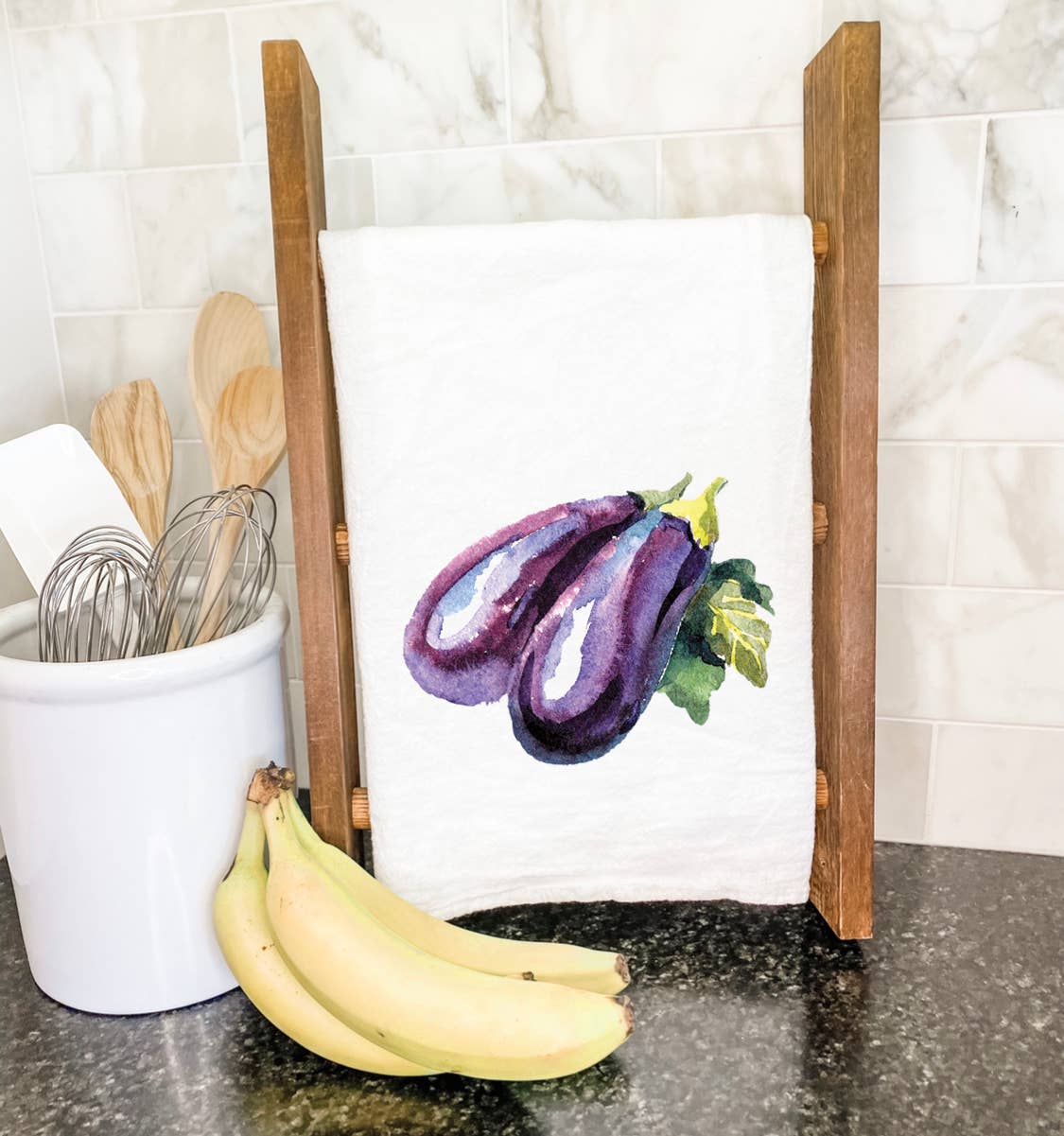 A vibrant eggplant design on a 100% cotton tea towel, showcasing its absorbent texture and hemmed edges.