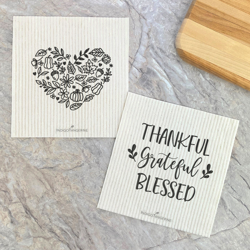 Two eco-friendly Swedish dish cloths with fall heart designs, made from plant-based fibers, displayed on a kitchen countertop.