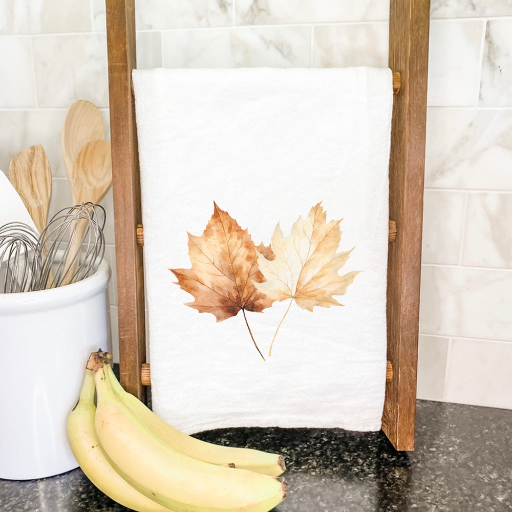 A vibrant cotton tea towel featuring a beautiful fall maple leaves design, perfect for kitchen use.