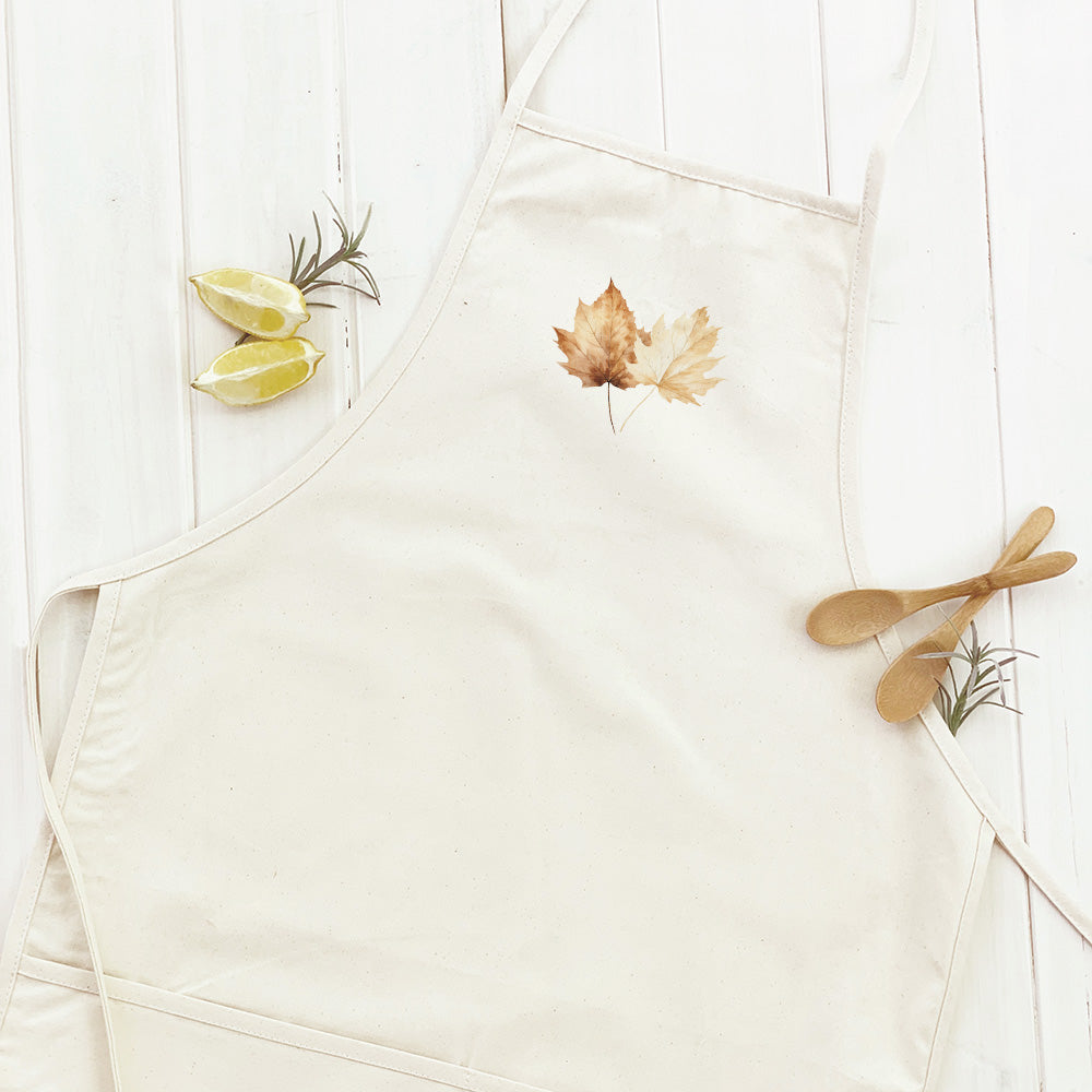 A stylish women's apron featuring a fall maple leaves design, made from durable cotton canvas with adjustable neck and twill ties.