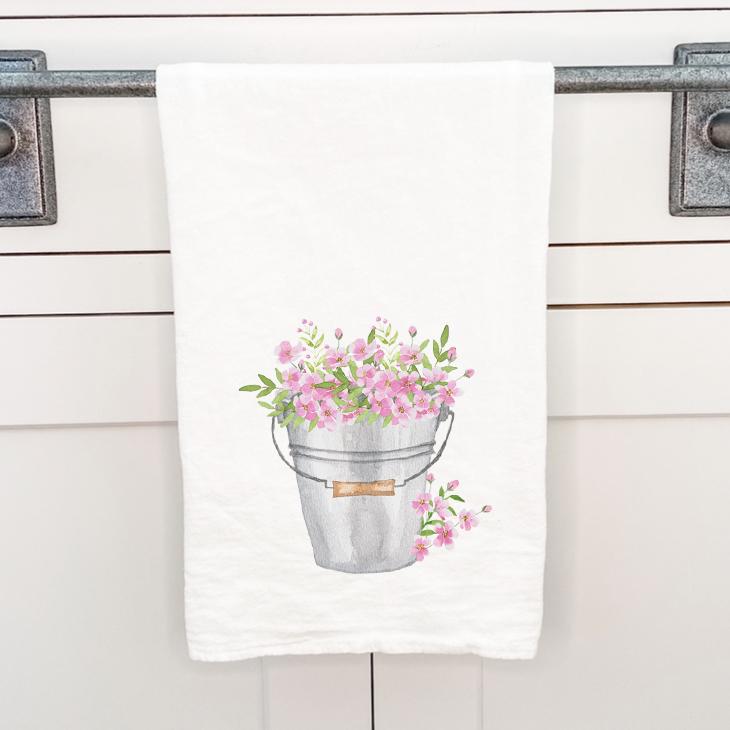 A vibrant cotton tea towel featuring a floral design, perfect for kitchen use, measuring 27 inches square.