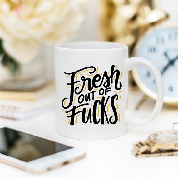 A humorous coffee mug with the phrase 'Fresh Out Of F*cks' printed on it, showcasing a fun design perfect for gag gifts.