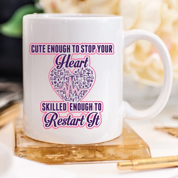 A humorous coffee mug for nurses featuring the phrase 'Cute Enough To Stop Your Heart, Skilled Enough To Restart It' with a vibrant design.