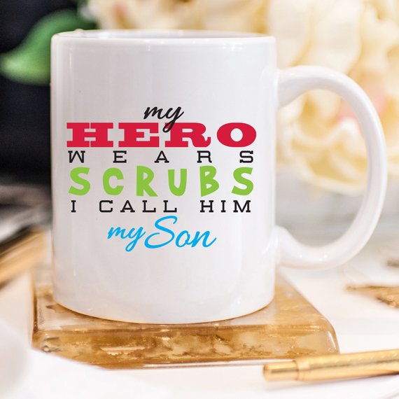 Funny Nurse Mug featuring the text 'My Hero Wears Scrubs, I Call Him My Son', perfect for coffee lovers and nursing professionals.