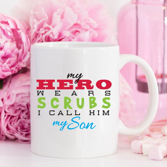 Funny Nurse Mug featuring the text 'My Hero Wears Scrubs, I Call Him My Son', perfect for coffee lovers and nursing professionals.