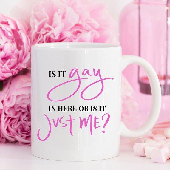 A colorful Gay Pride Mug featuring the humorous phrase 'Is It Gay In Here Or Is It Just Me?' designed for coffee lovers.