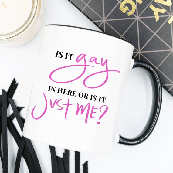 A colorful Gay Pride Mug featuring the humorous phrase 'Is It Gay In Here Or Is It Just Me?' designed for coffee lovers.