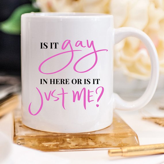 A colorful Gay Pride Mug featuring the humorous phrase 'Is It Gay In Here Or Is It Just Me?' designed for coffee lovers.