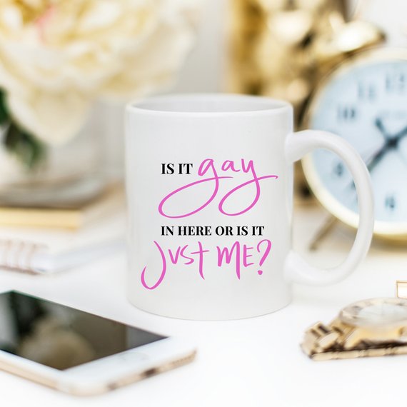 A colorful Gay Pride Mug featuring the humorous phrase 'Is It Gay In Here Or Is It Just Me?' designed for coffee lovers.