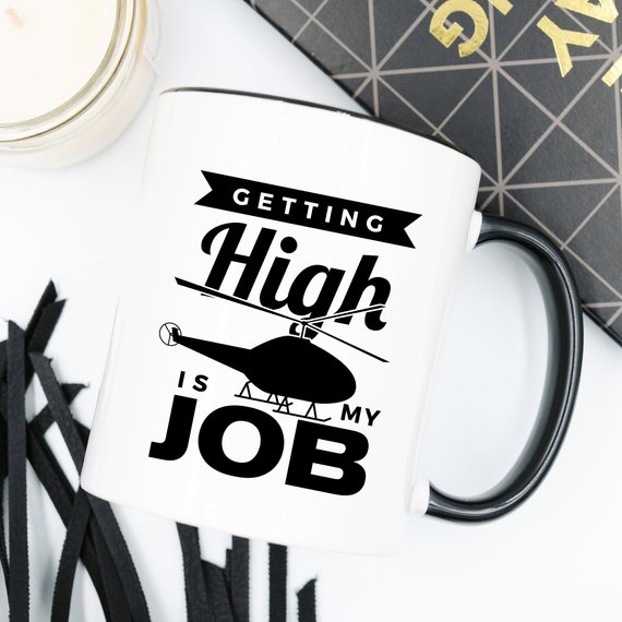 A humorous coffee mug with the phrase 'Getting High Is My Job' printed on it, showcasing a fun design perfect for coffee lovers.