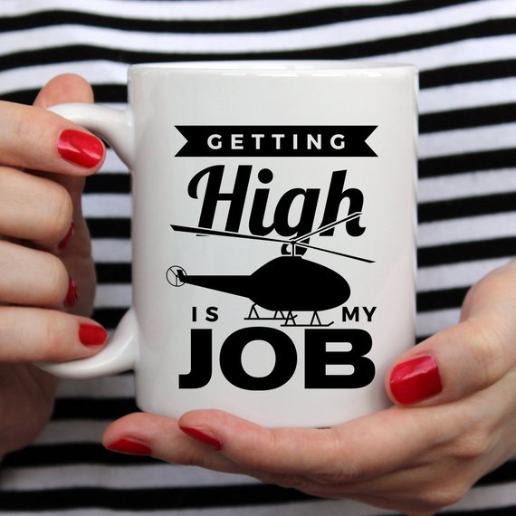 A humorous coffee mug with the phrase 'Getting High Is My Job' printed on it, showcasing a fun design perfect for coffee lovers.