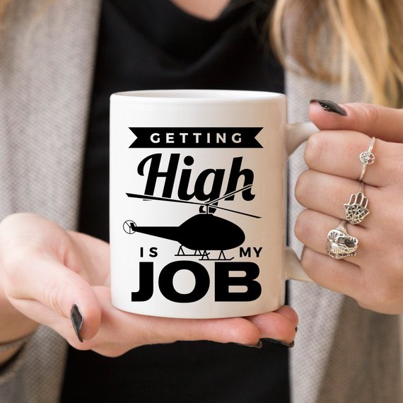 A humorous coffee mug with the phrase 'Getting High Is My Job' printed on it, showcasing a fun design perfect for coffee lovers.