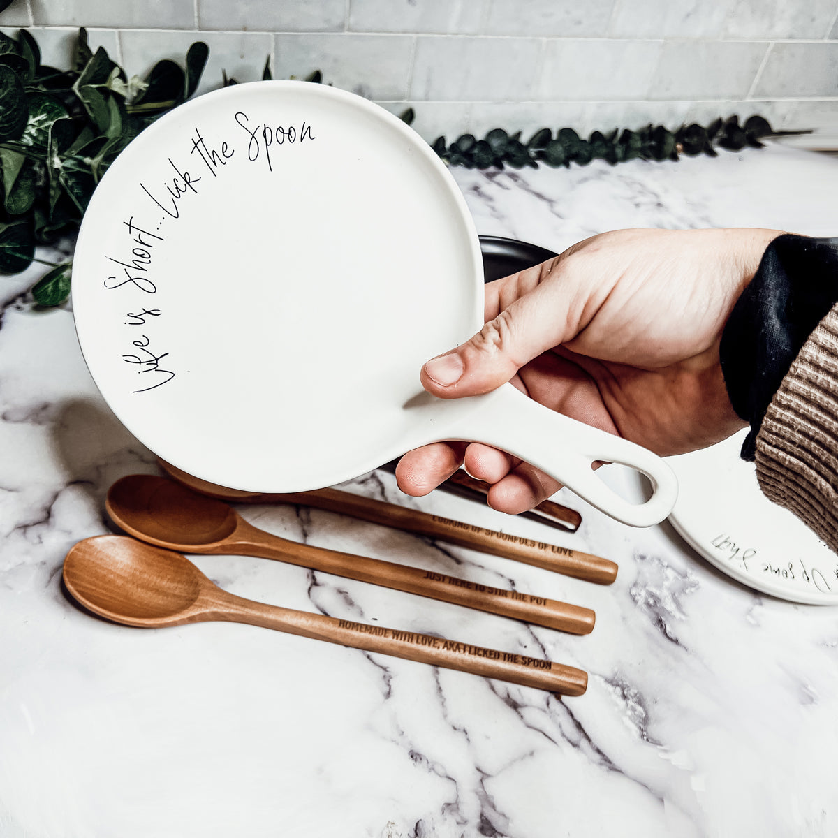 Give it a Rest LG spoon rest and wooden spoon set featuring various colors and fun quotes, perfect for keeping your kitchen clean.