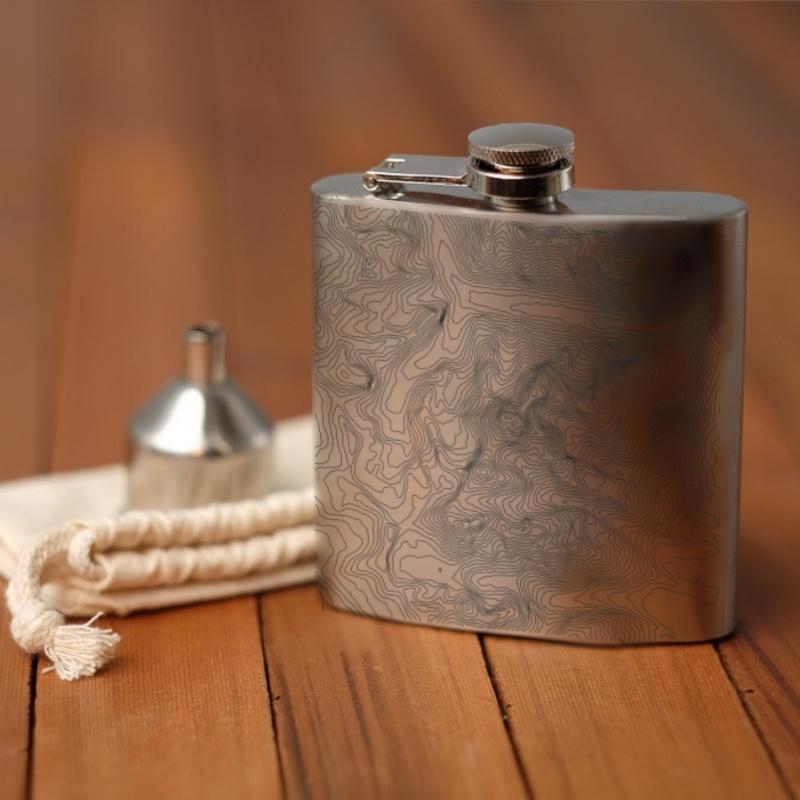 Matte black hip flask featuring a custom engraved map of Grand Teton National Park, complete with coordinates and a canvas bag.