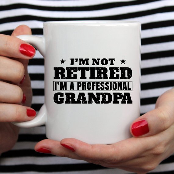 A humorous coffee mug featuring the phrase 'I'm Not Retired, I'm A Professional Grandpa', showcasing a fun design perfect for grandparents.