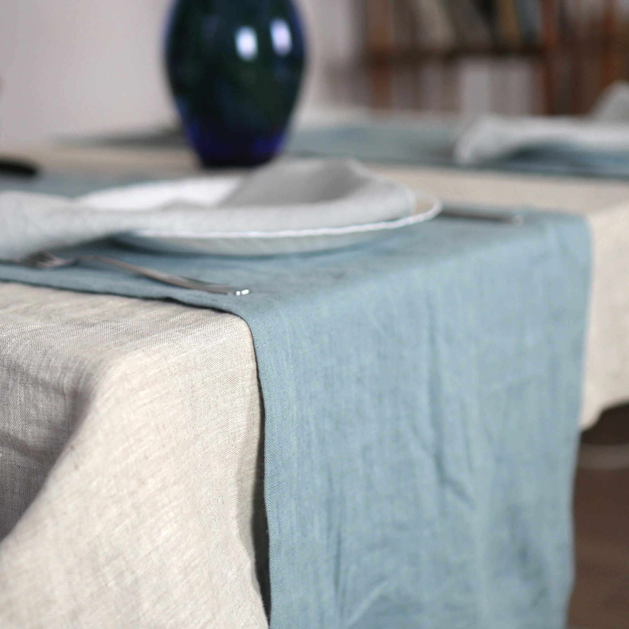 Greyish Mint linen table runner elegantly displayed on a dining table, showcasing its minimalist design and decorative hem.