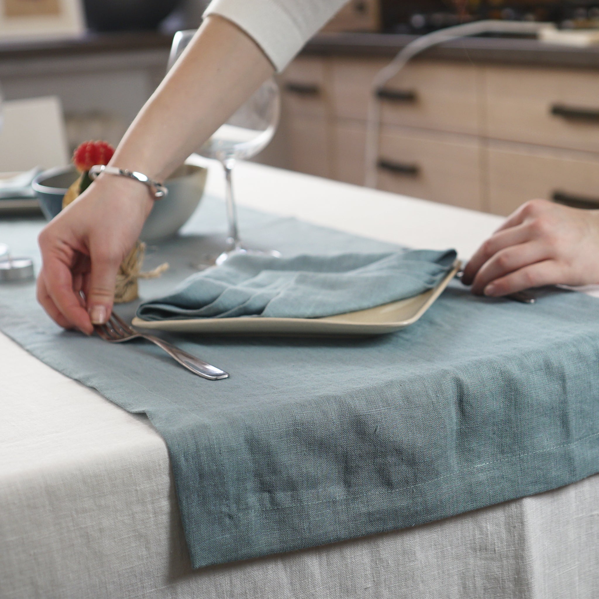 Greyish Mint linen table runner elegantly displayed on a dining table, showcasing its minimalist design and decorative hem.