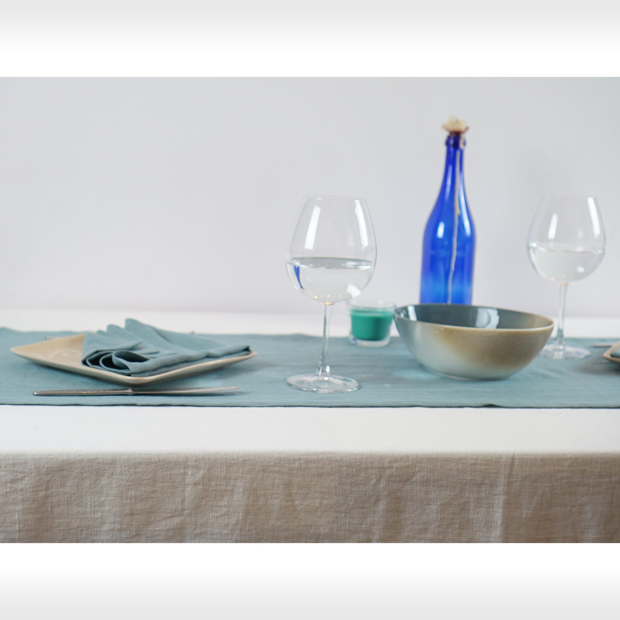 Greyish Mint linen table runner elegantly displayed on a dining table, showcasing its minimalist design and decorative hem.