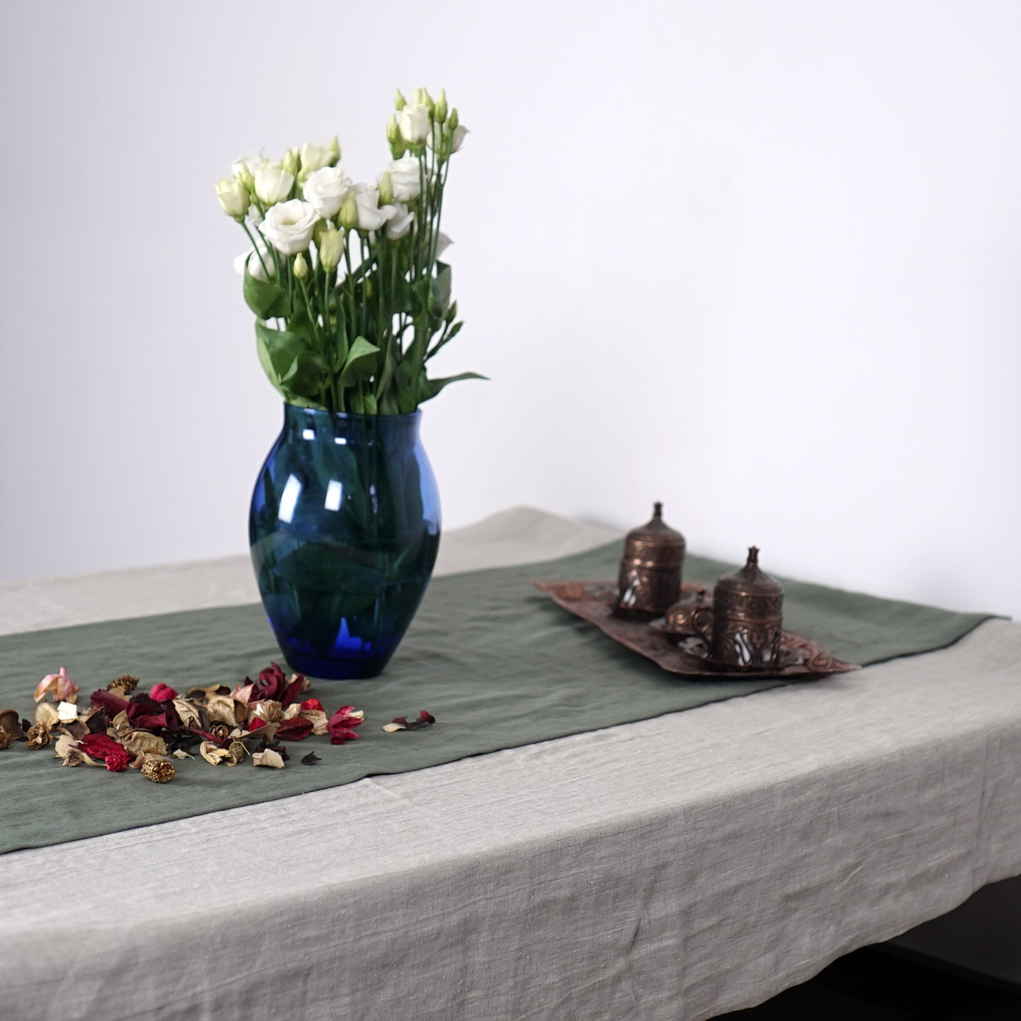 Greyish Mint linen table runner elegantly displayed on a dining table, showcasing its minimalist design and decorative hem.