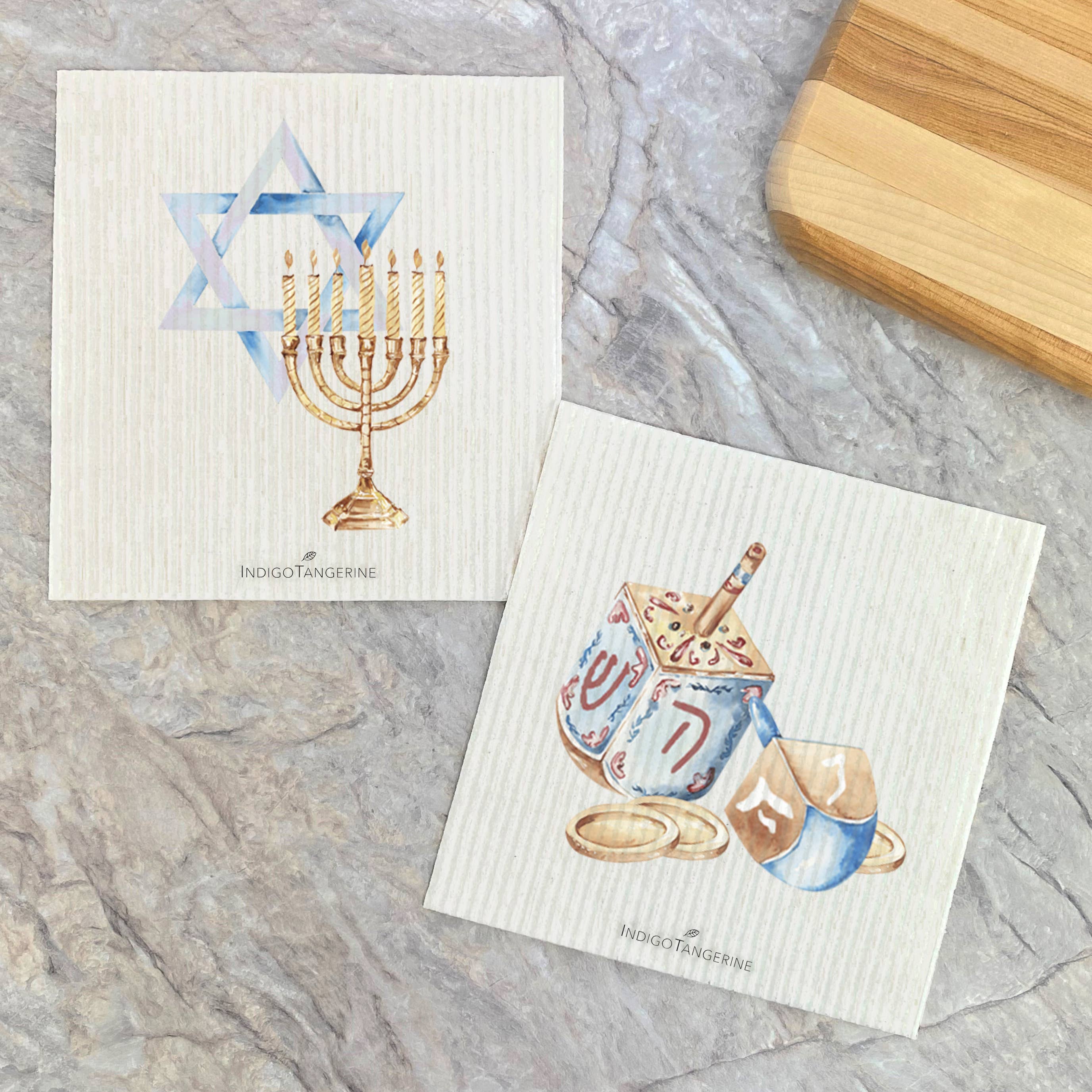 Two Swedish dish cloths featuring Hanukkah designs of a dreidel and menorah, eco-friendly and reusable.