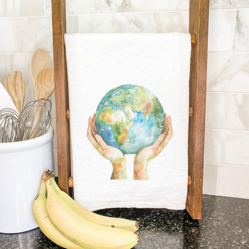 Holding the World cotton tea towel featuring vibrant design and hemmed edges, perfect for kitchen use.