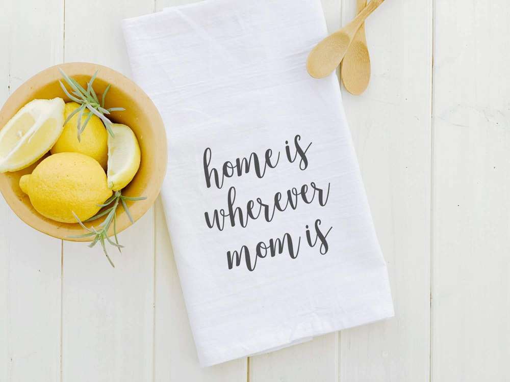 A vibrant cotton tea towel featuring the phrase 'Home Is Wherever Mom Is', designed with a beautiful print and hemmed edges.