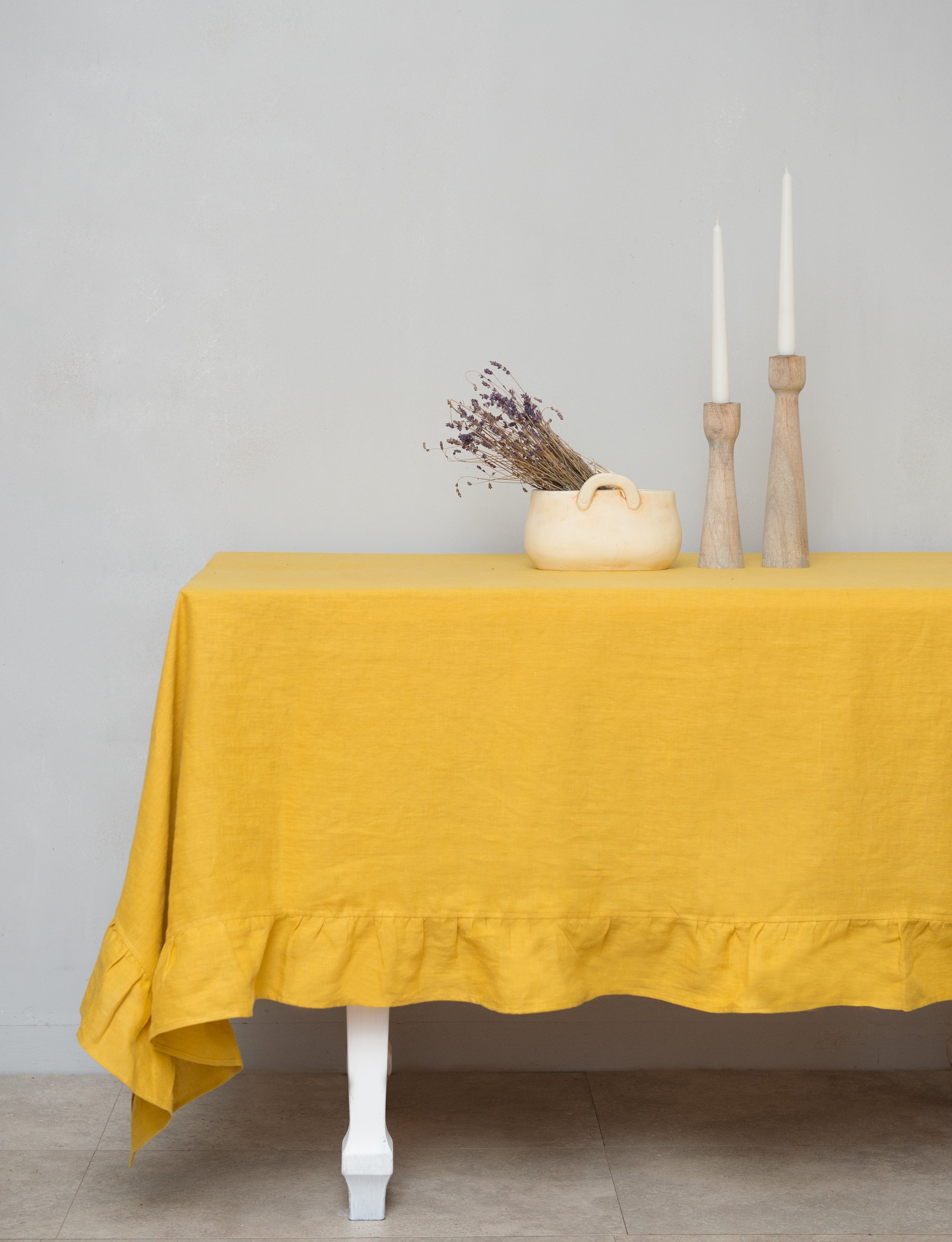 Bright honey-colored linen tablecloth with elegant ruffles, showcasing its luxurious texture and drape.