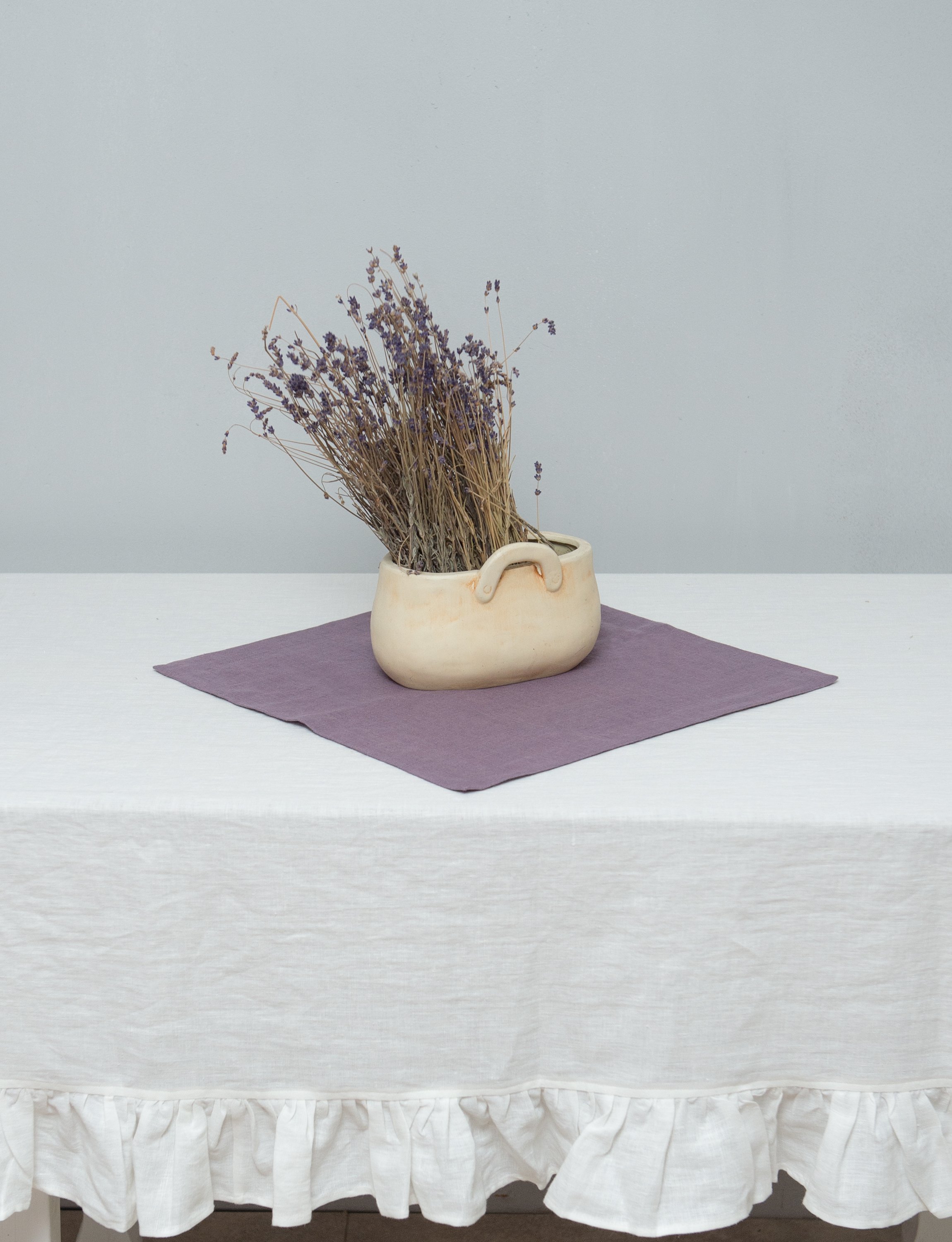 Bright honey-colored linen tablecloth with elegant ruffles, showcasing its luxurious texture and drape.