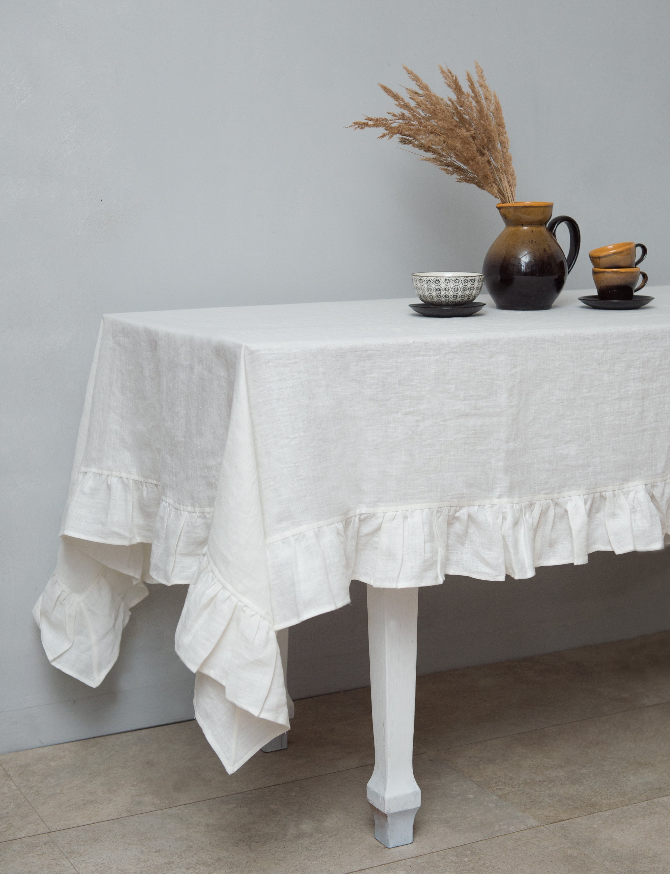 Bright honey-colored linen tablecloth with elegant ruffles, showcasing its luxurious texture and drape.