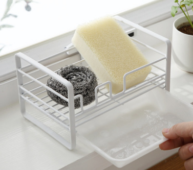 Household rack for kitchen sponges and brushes with a detachable drain basket, featuring a sleek white design and non-slip footpad.