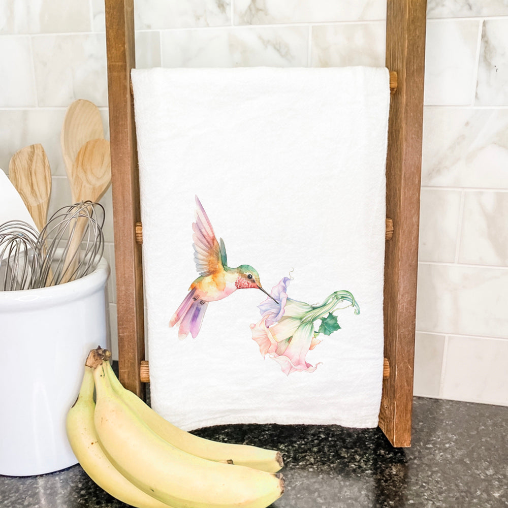 A vibrant cotton tea towel featuring a hummingbird and trumpet flower design, showcasing its colorful and artistic print.