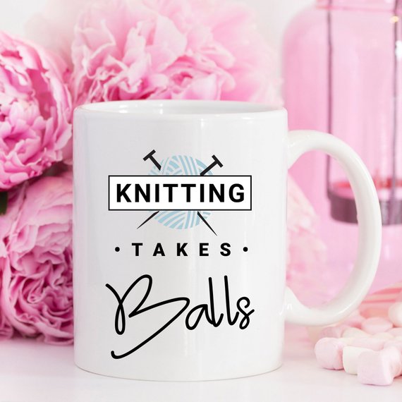 A humorous coffee mug with the phrase 'Knitting Takes Balls', featuring a colorful design perfect for knitting enthusiasts.