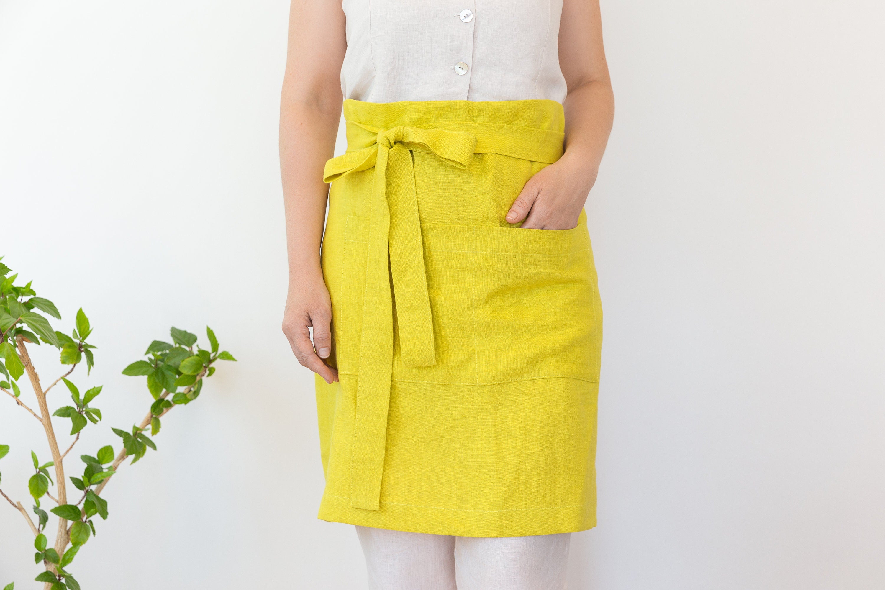 Lemon linen waist apron with pockets and ties, showcasing its vibrant color and soft texture, perfect for kitchen use.