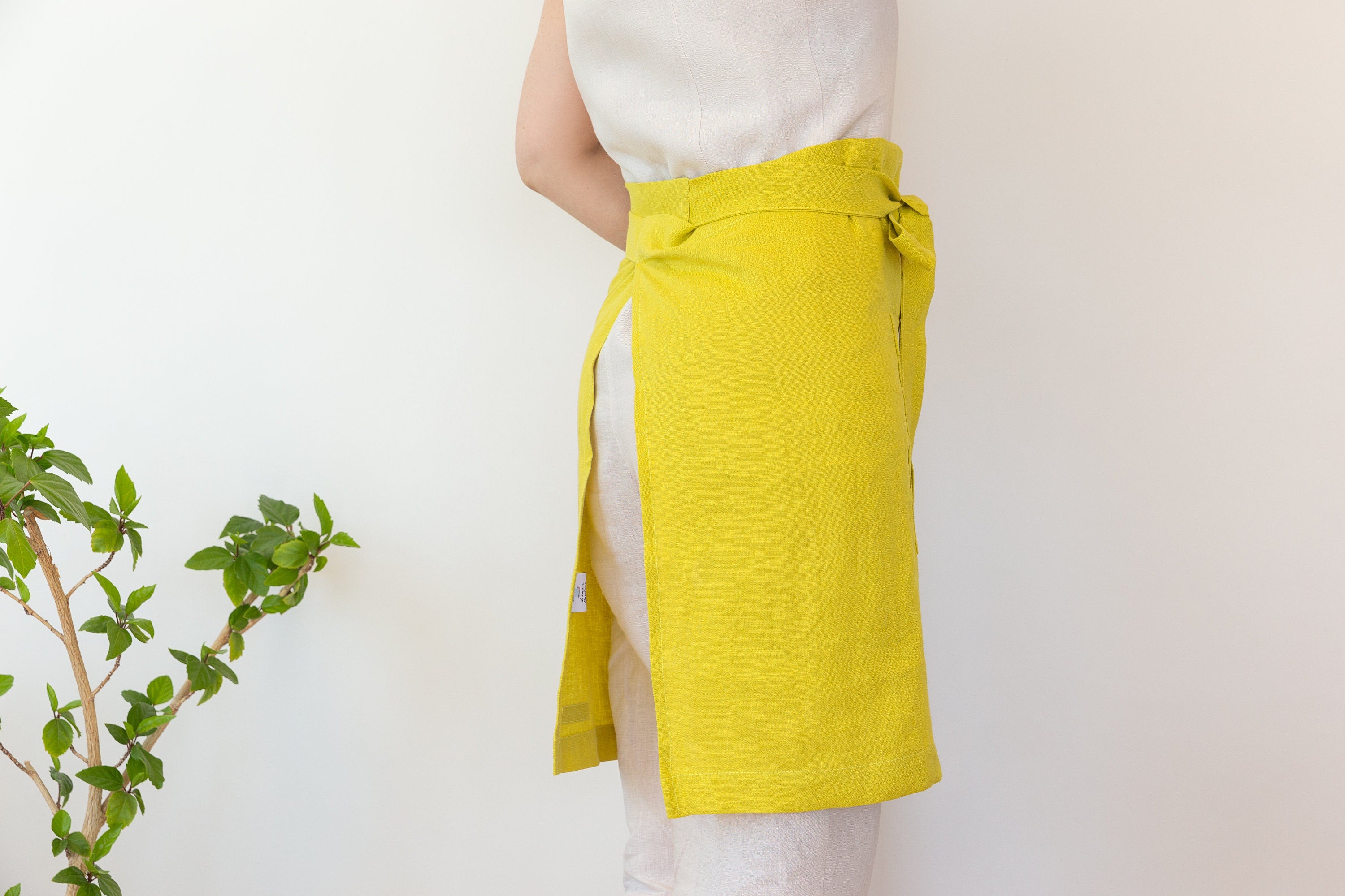 Lemon linen waist apron with pockets and ties, showcasing its vibrant color and soft texture, perfect for kitchen use.