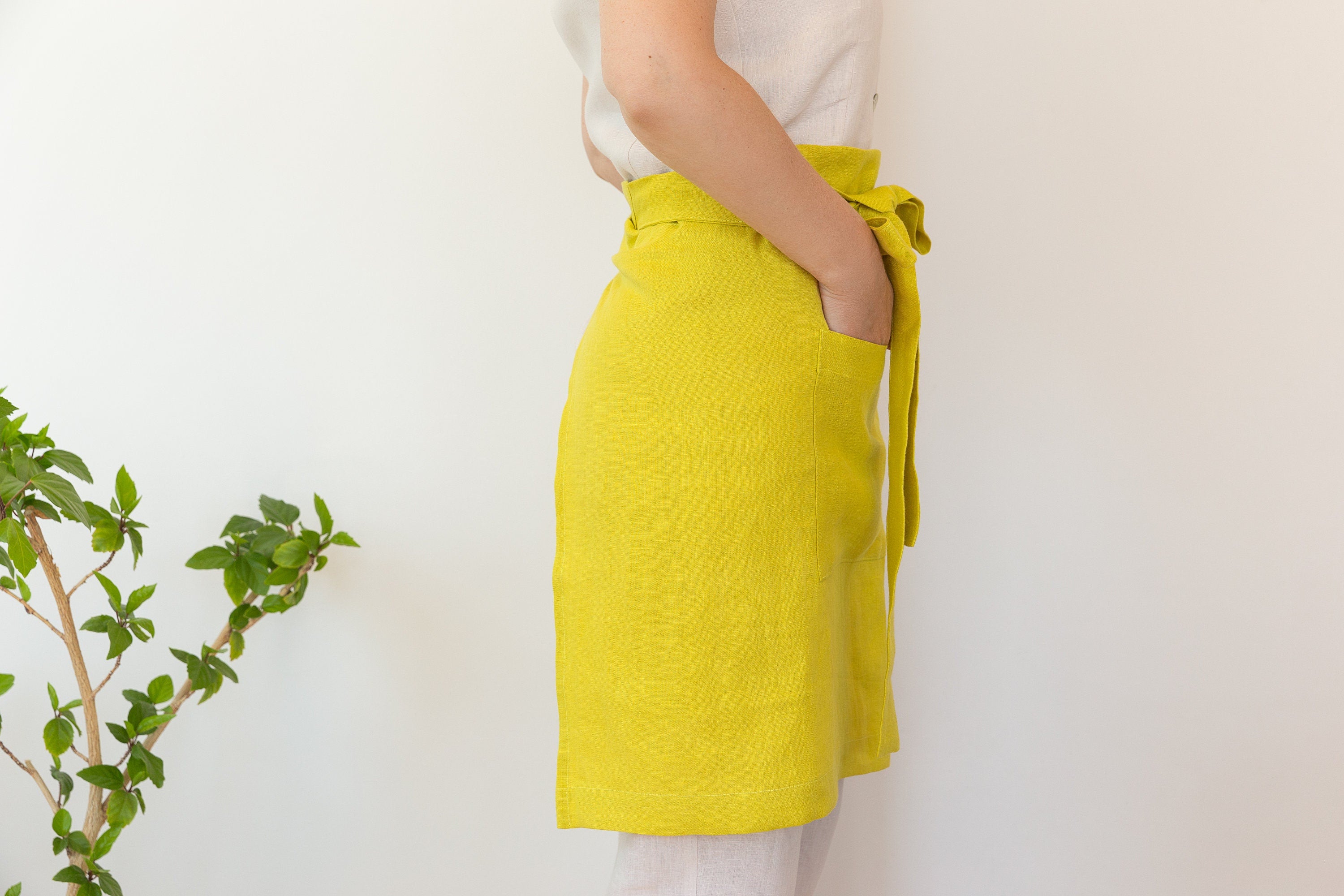 Lemon linen waist apron with pockets and ties, showcasing its vibrant color and soft texture, perfect for kitchen use.