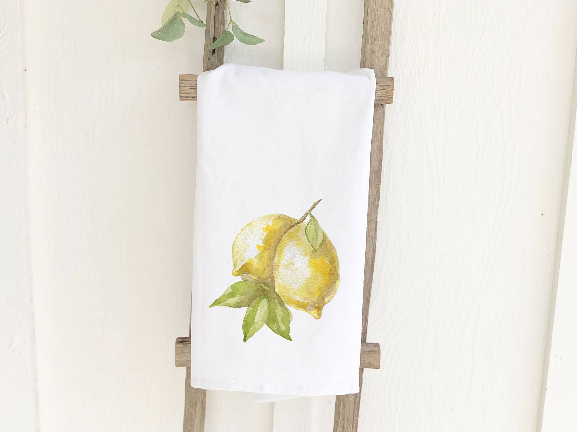 A vibrant cotton tea towel featuring a lemon design, perfect for kitchen use, showcasing its absorbent texture and hemmed edges.