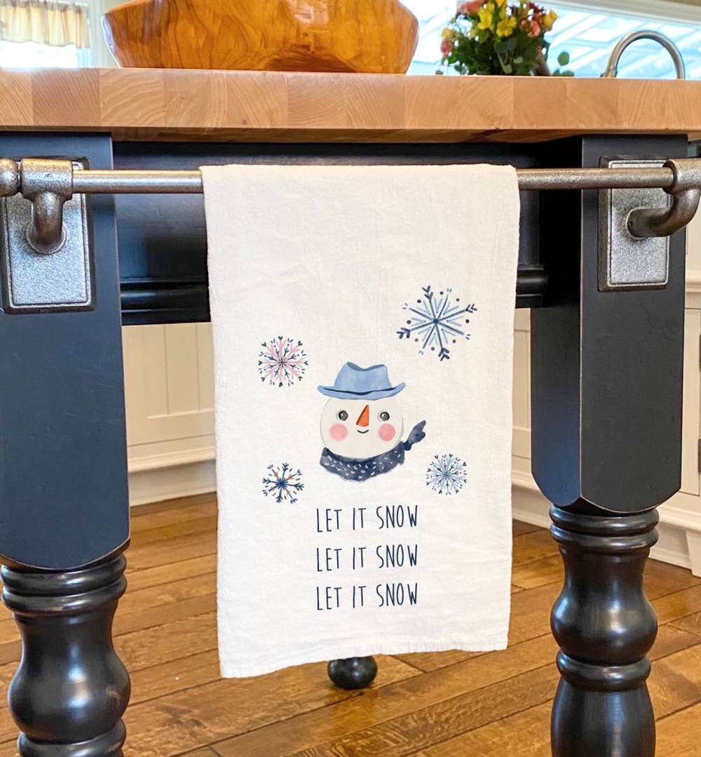 Let it Snow Snowman Cotton Tea Towel featuring a cheerful snowman design, made from 100% absorbent cotton, perfect for holiday kitchen decor.