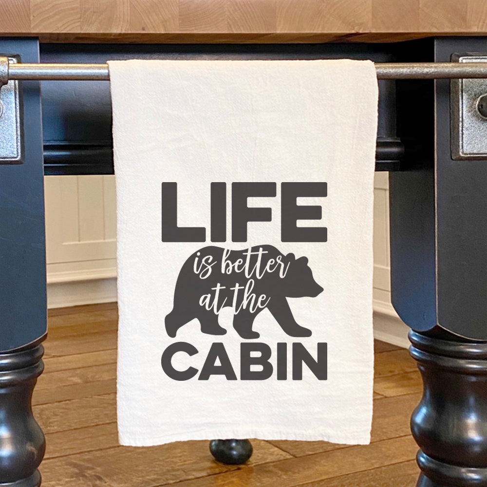 Cotton tea towel featuring a bear design with the phrase 'Life is Better at the Cabin', perfect for kitchen use.