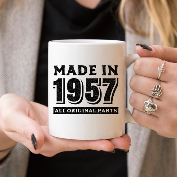 A humorous coffee mug featuring the text 'Made In 1957, All Original Parts - Funny Coffee Mug', showcasing a vibrant design perfect for 61st birthday celebrations.