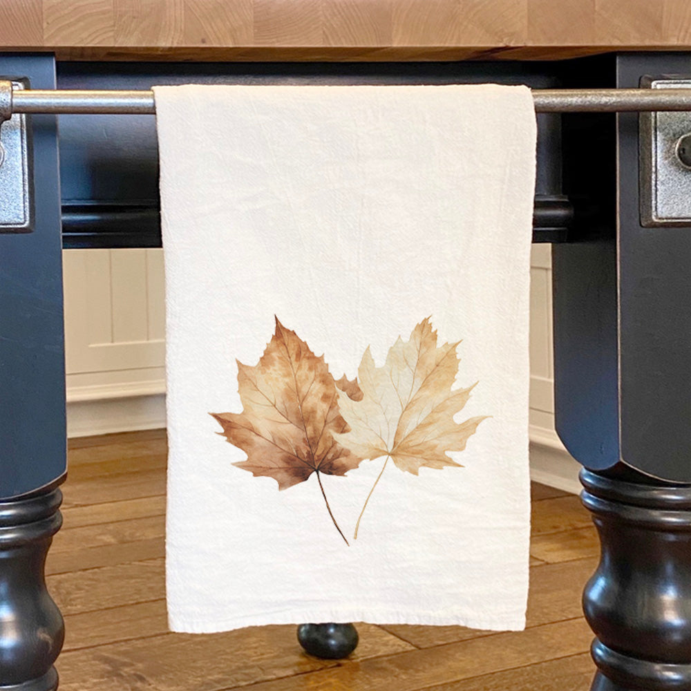 A beautifully designed cotton tea towel featuring vibrant maple leaves, perfect for kitchen use.