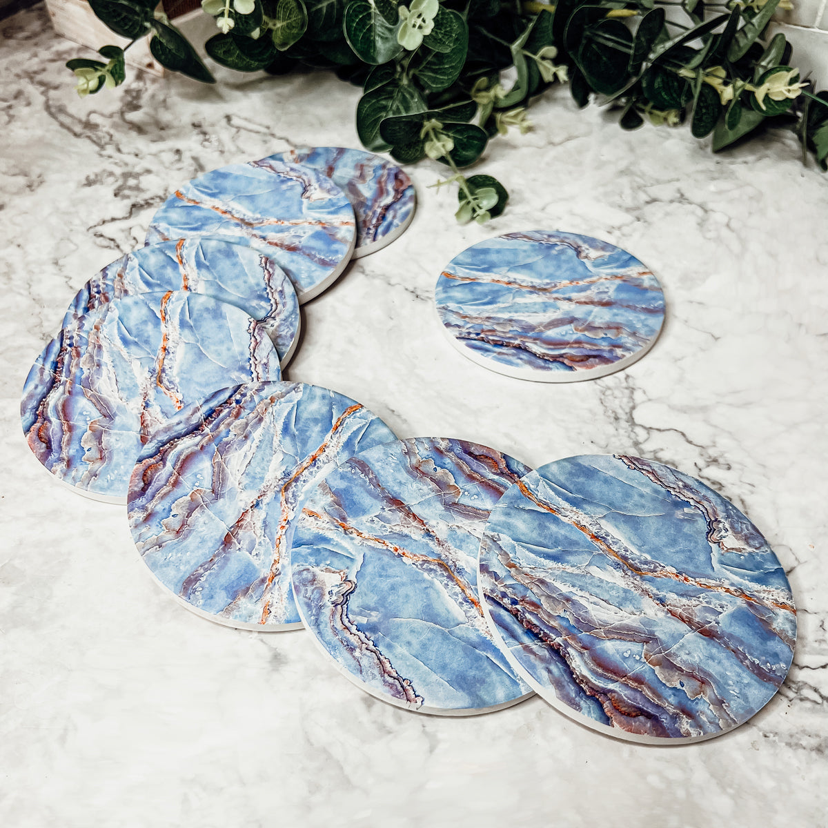 Set of four luxurious Marble Blue Coasters with a watercolor effect, featuring shades of blue and gold accents, displayed in a brown box.