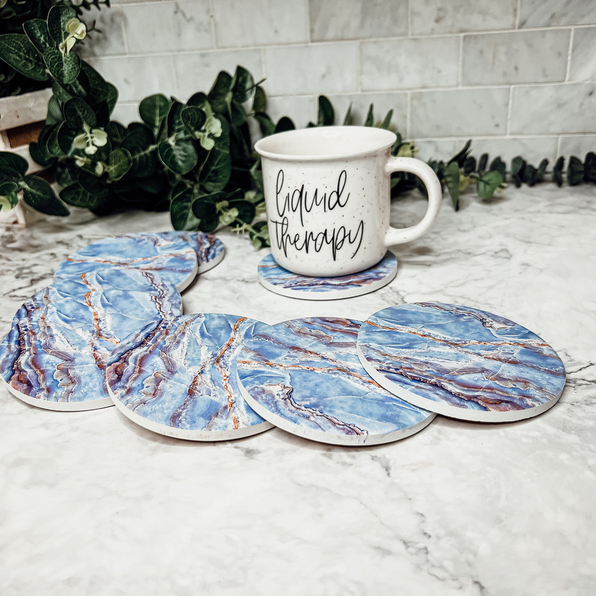 Set of four luxurious Marble Blue Coasters with a watercolor effect, featuring shades of blue and gold accents, displayed in a brown box.