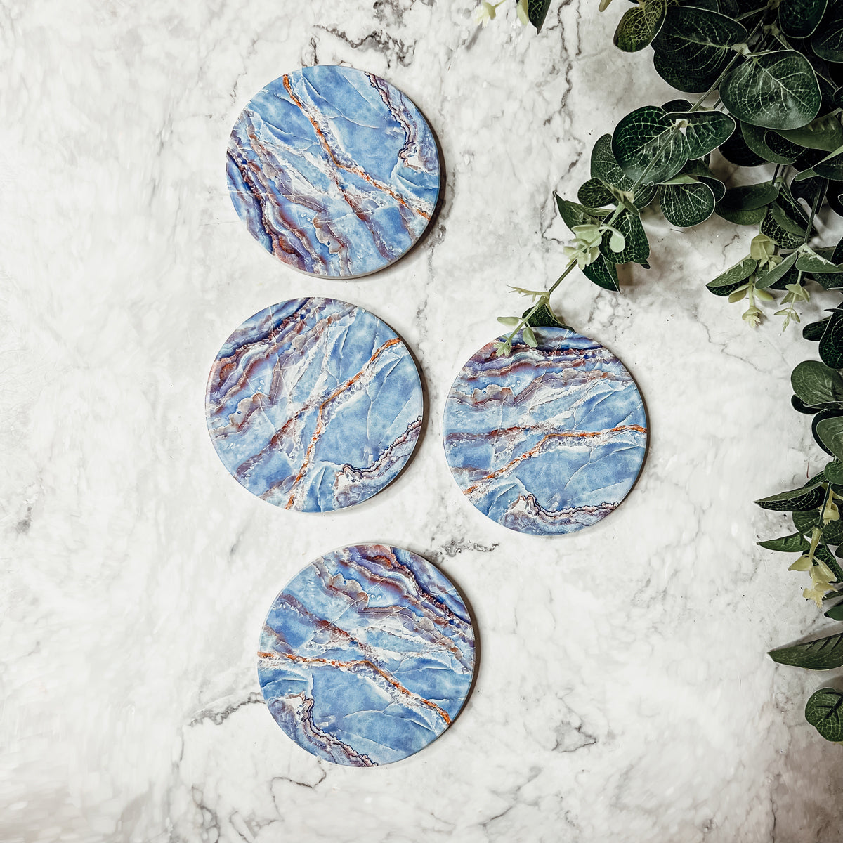 Set of four luxurious Marble Blue Coasters with a watercolor effect, featuring shades of blue and gold accents, displayed in a brown box.