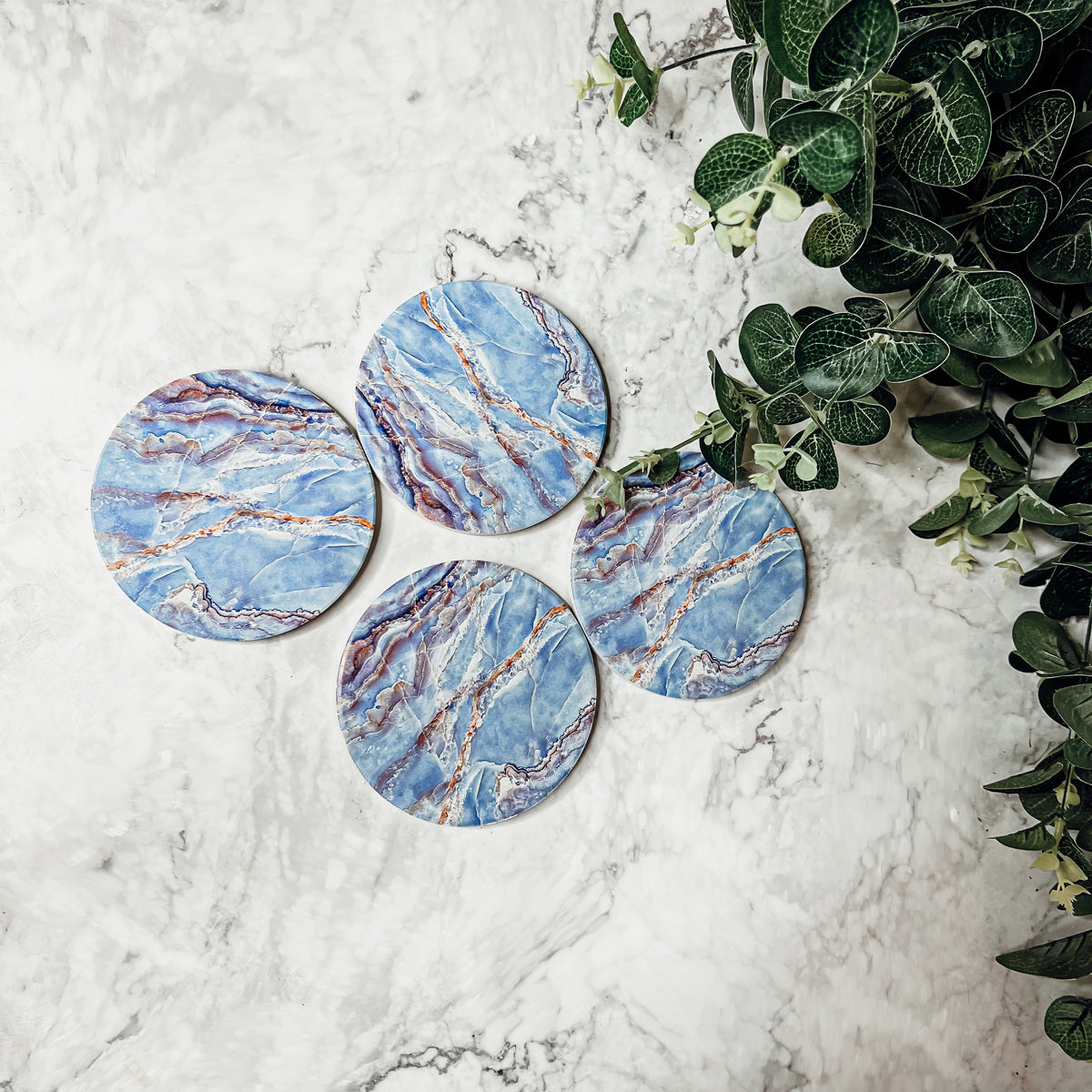 Set of four luxurious Marble Blue Coasters with a watercolor effect, featuring shades of blue and gold accents, displayed in a brown box.