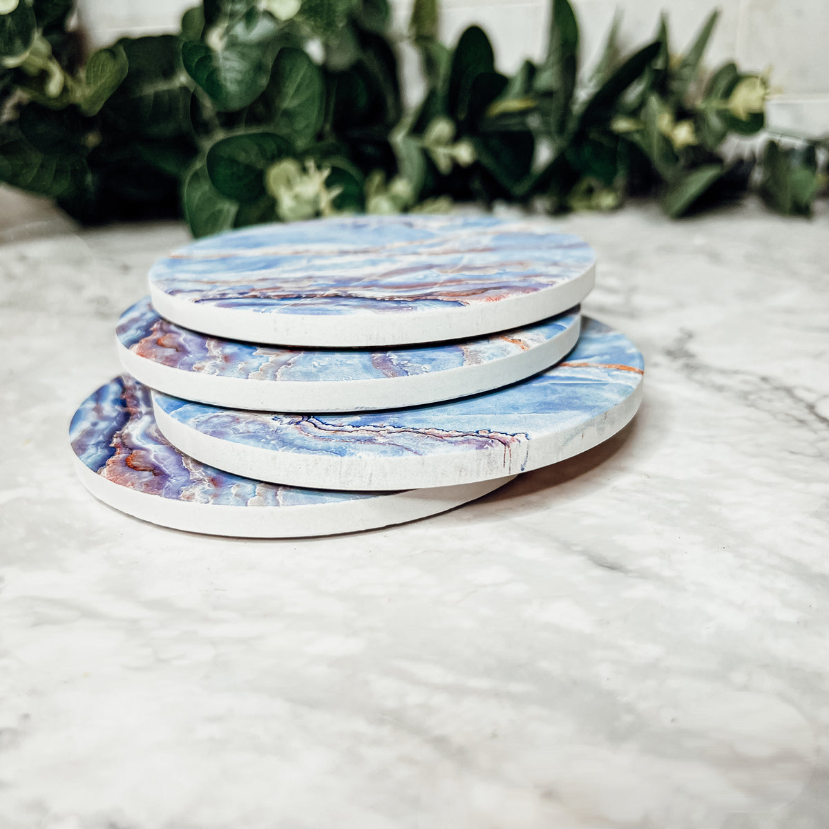 Set of four luxurious Marble Blue Coasters with a watercolor effect, featuring shades of blue and gold accents, displayed in a brown box.