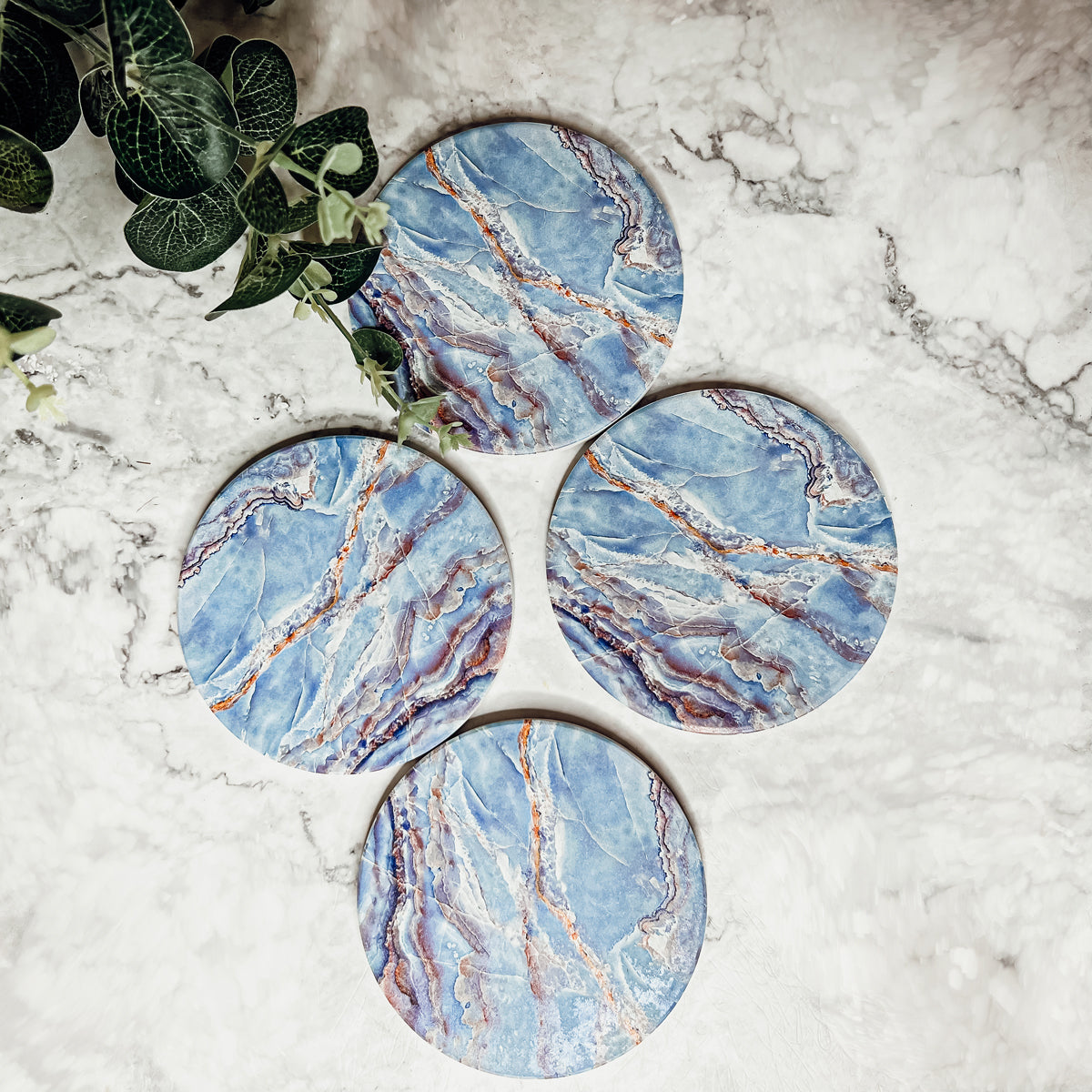 Set of four luxurious Marble Blue Coasters with a watercolor effect, featuring shades of blue and gold accents, displayed in a brown box.