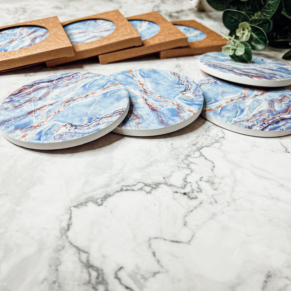 Set of four luxurious Marble Blue Coasters with a watercolor effect, featuring shades of blue and gold accents, displayed in a brown box.