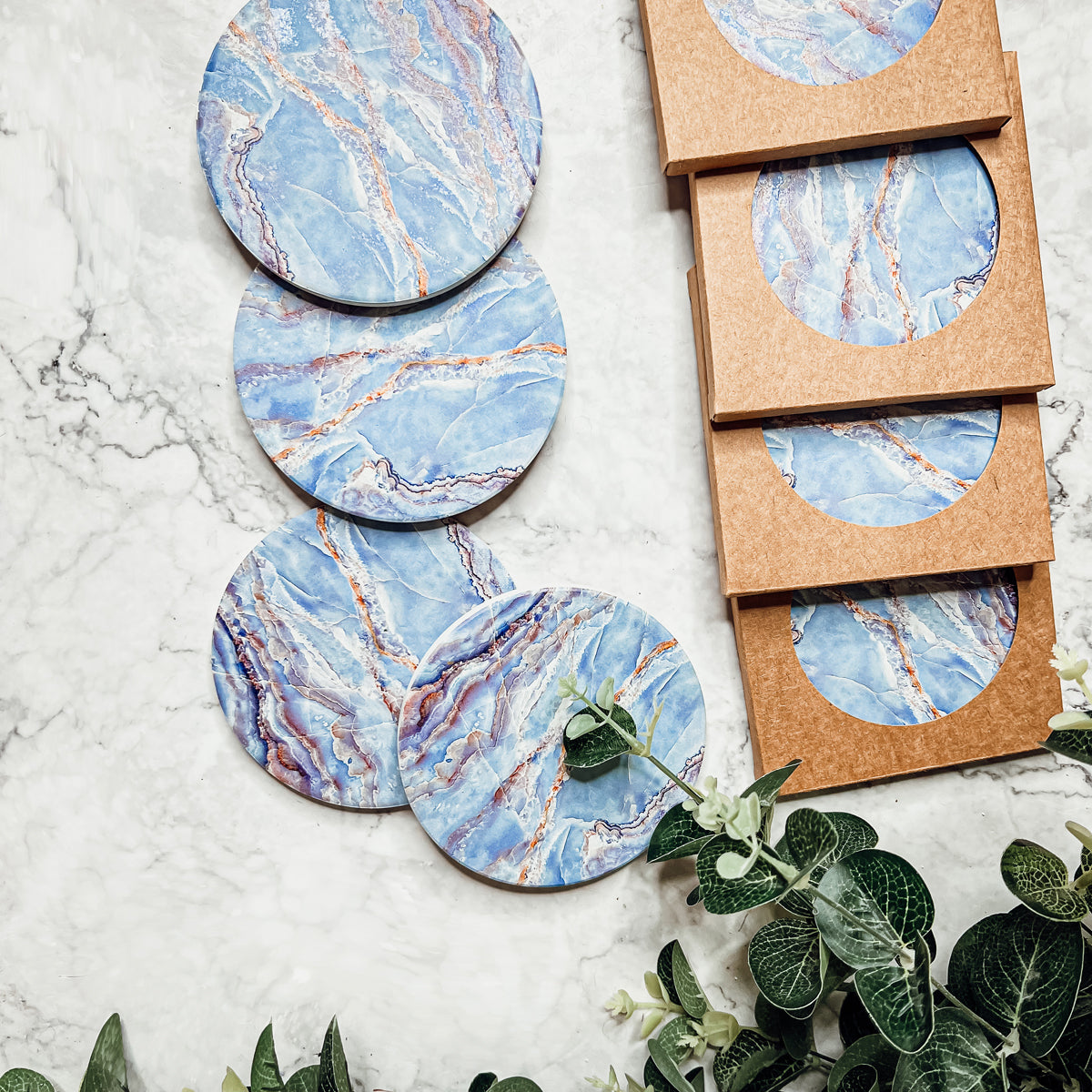 Set of four luxurious Marble Blue Coasters with a watercolor effect, featuring shades of blue and gold accents, displayed in a brown box.