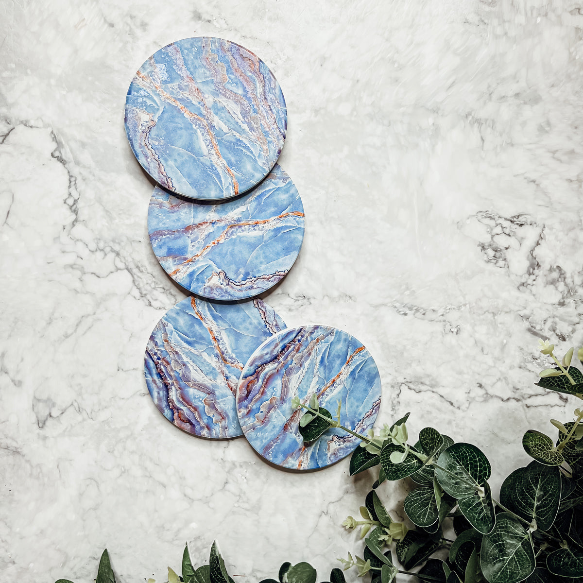 Set of four luxurious Marble Blue Coasters with a watercolor effect, featuring shades of blue and gold accents, displayed in a brown box.