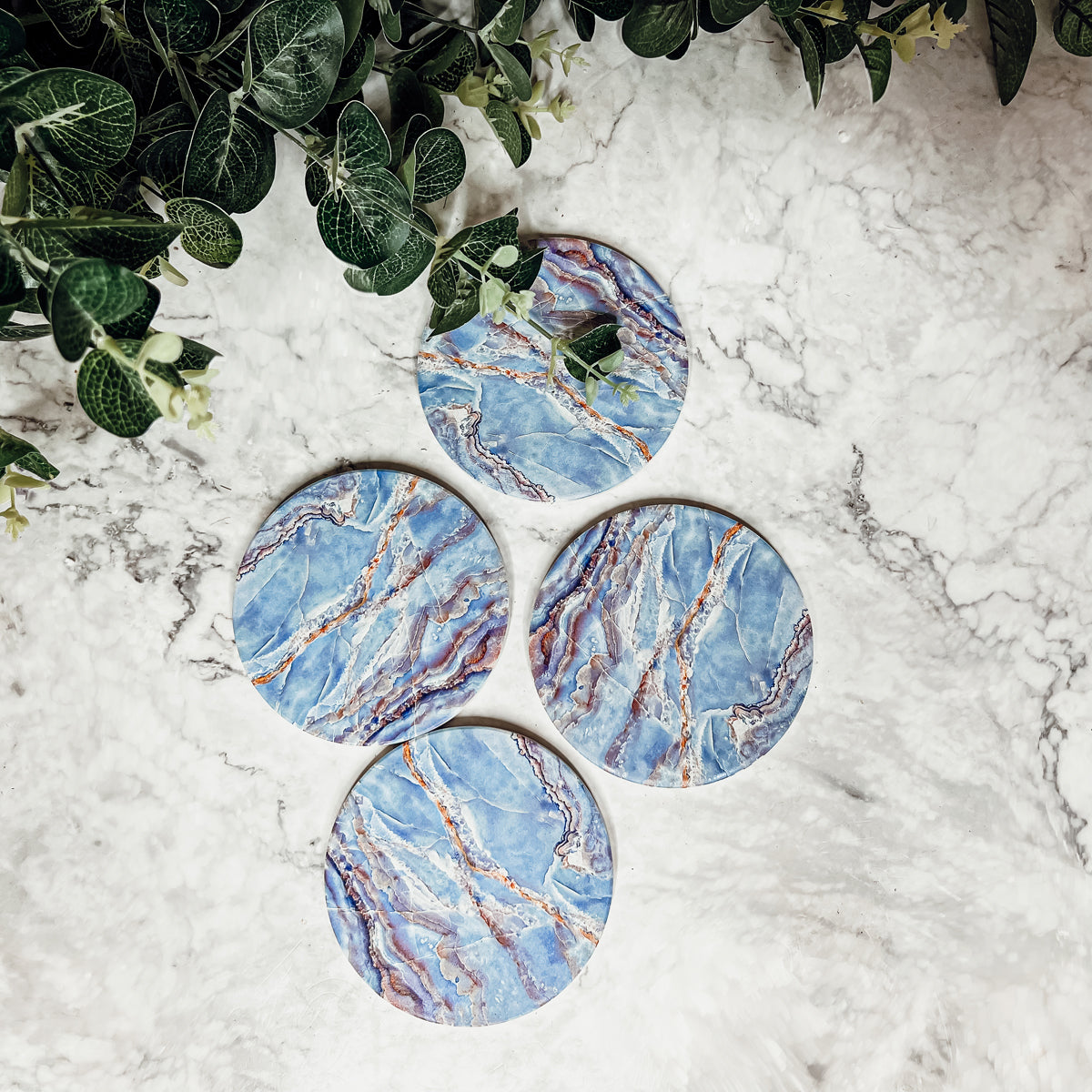 Set of four luxurious Marble Blue Coasters with a watercolor effect, featuring shades of blue and gold accents, displayed in a brown box.